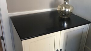 A white cabinet with a black countertop, a lamp, and a wall-mounted light switch. - Perfect Getaway overlooking the Puget Sound, Close to Ruston Point and UPS (Tacoma)