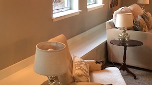 A cozy living room with a sofa, two side tables with lamps, a framed picture on the wall, and a window with a view of greenery. - Perfect Getaway overlooking the Puget Sound, Close to Ruston Point and UPS (Tacoma)