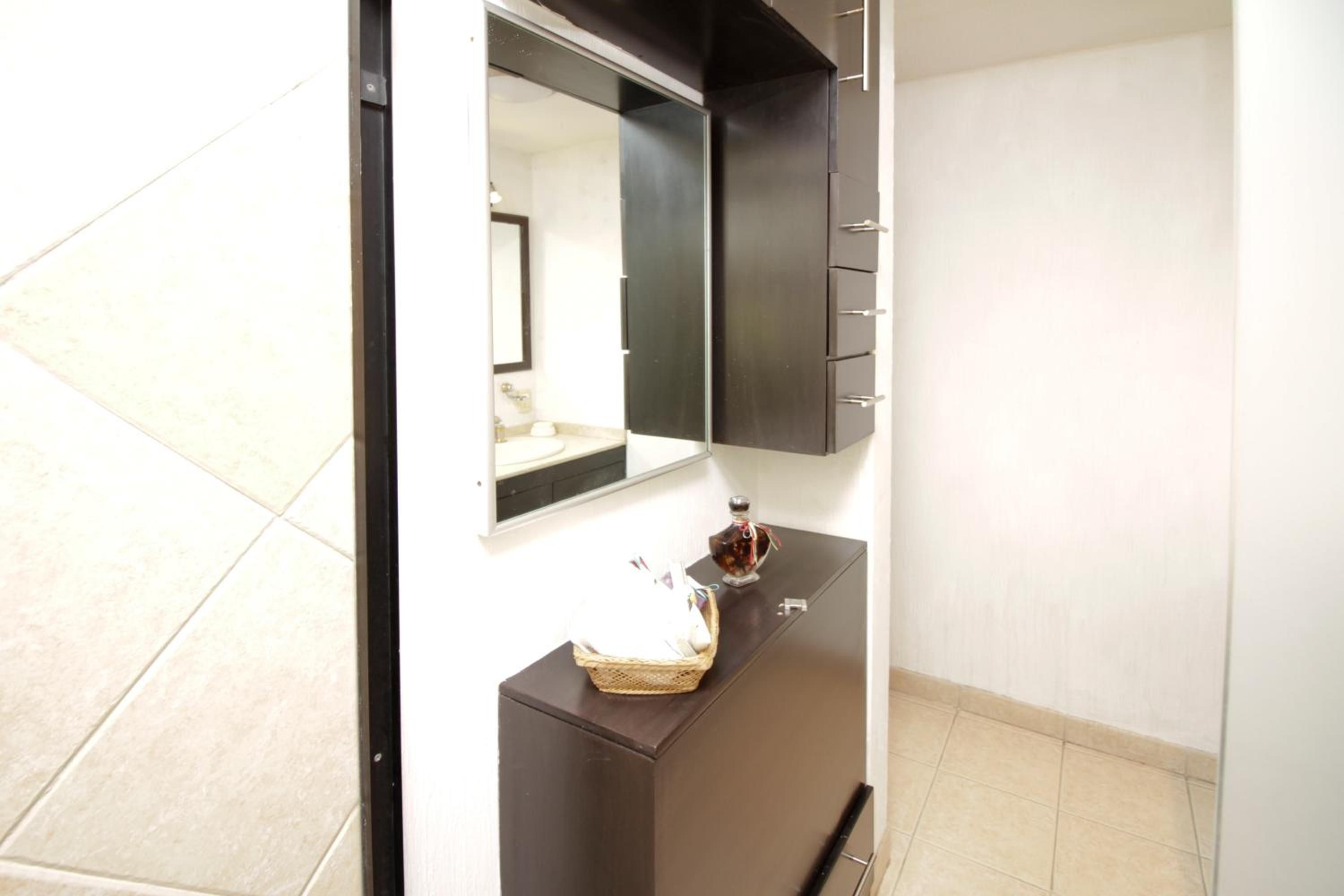 Un baño con tocador oscuro, un espejo y un lavamanos pequeño.