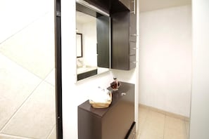 A bathroom with a dark vanity, a mirror, and a small sink.