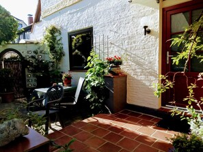 A patio with a table and chairs, a potted plant, and a red door. - Apartment Käding in Kappeln an der Schlei - Apartment Käding in Kappeln an der Schlei (Kappeln)