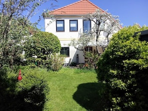 A house with a red roof, a white exterior, and a well-maintained garden with various plants and a lawn. - Apartment Käding in Kappeln an der Schlei - Apartment Käding in Kappeln an der Schlei (Kappeln)