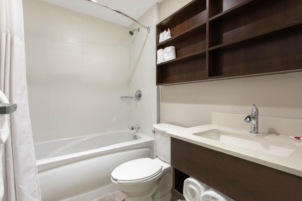 Un baño moderno con bañera, inodoro y tocador con estantes.