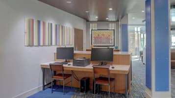 Un espacio de oficina moderno con dos escritorios, sillas, computadoras y obras de arte en las paredes.