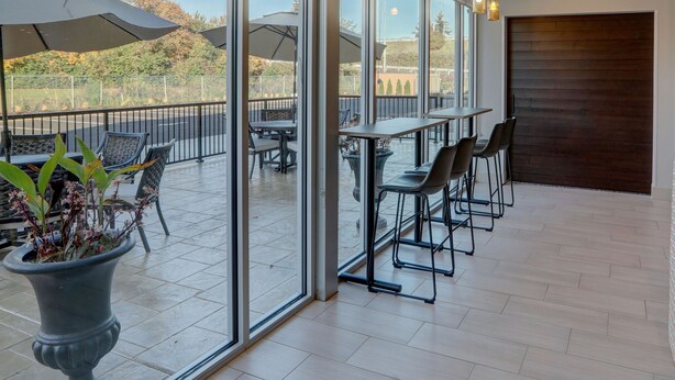 A spacious indoor area with large windows, multiple tables and chairs, and hanging pendant lights. - Holiday Inn Express & Suites Auburn Downtown by IHG (Auburn)