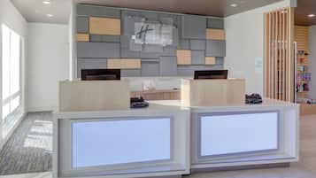 Una reception dal design moderno, con banco check-in e un display a parete.