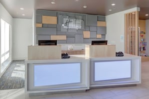 A reception desk with a modern design, a check-in counter, and a wall-mounted display. - Holiday Inn Express & Suites Auburn Downtown by IHG (Auburn)