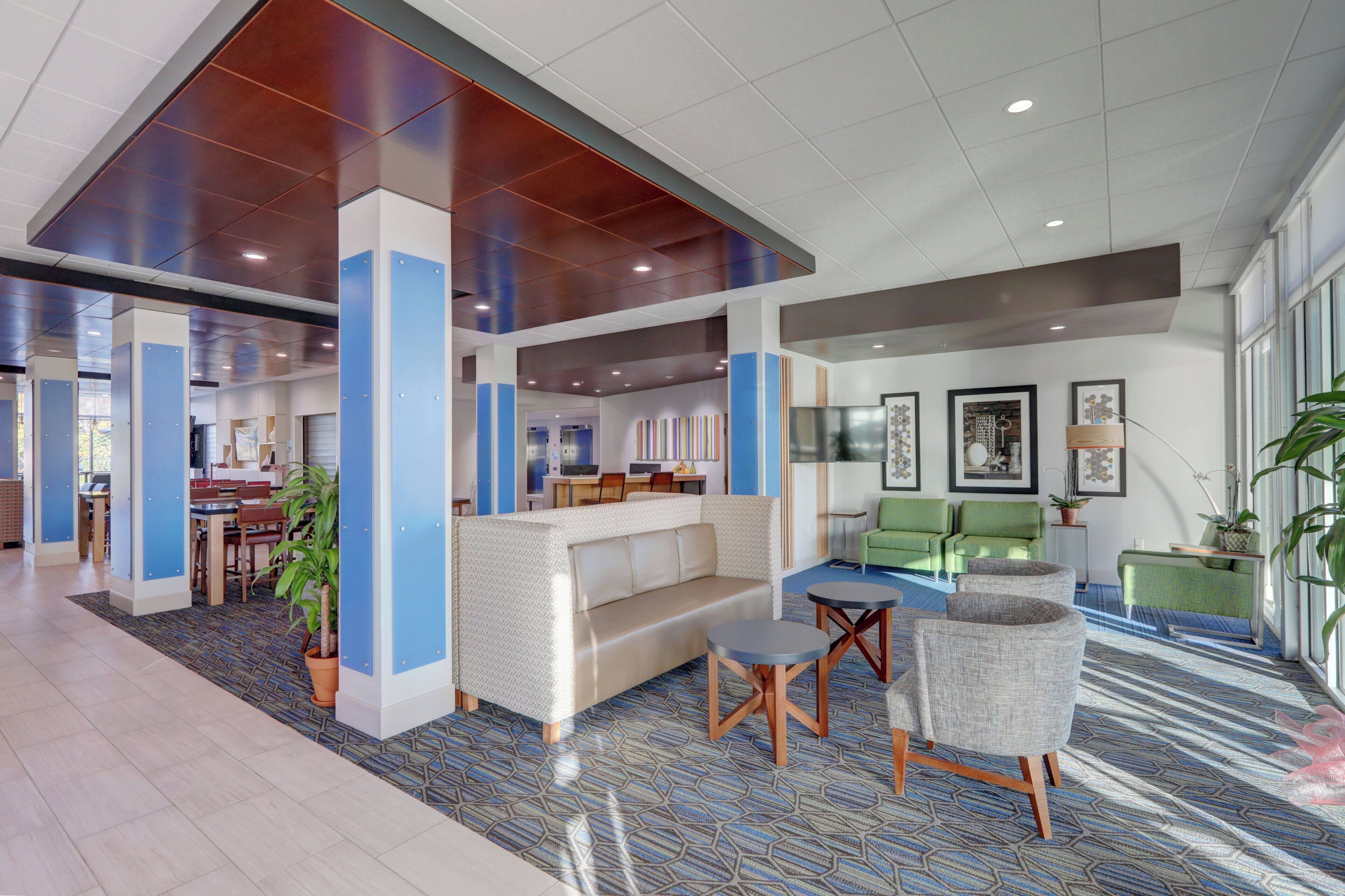 A modern lobby with a reception desk, seating area, and a large window providing natural light.