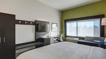 Une chambre d’hôtel avec un grand lit, un bureau, une chaise, une télévision et une fenêtre donnant sur un beau paysage.