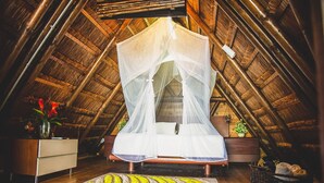 A bed with a white canopy in a room with wooden walls and a thatched roof. - Imagine Beach (Puerto Colombia)