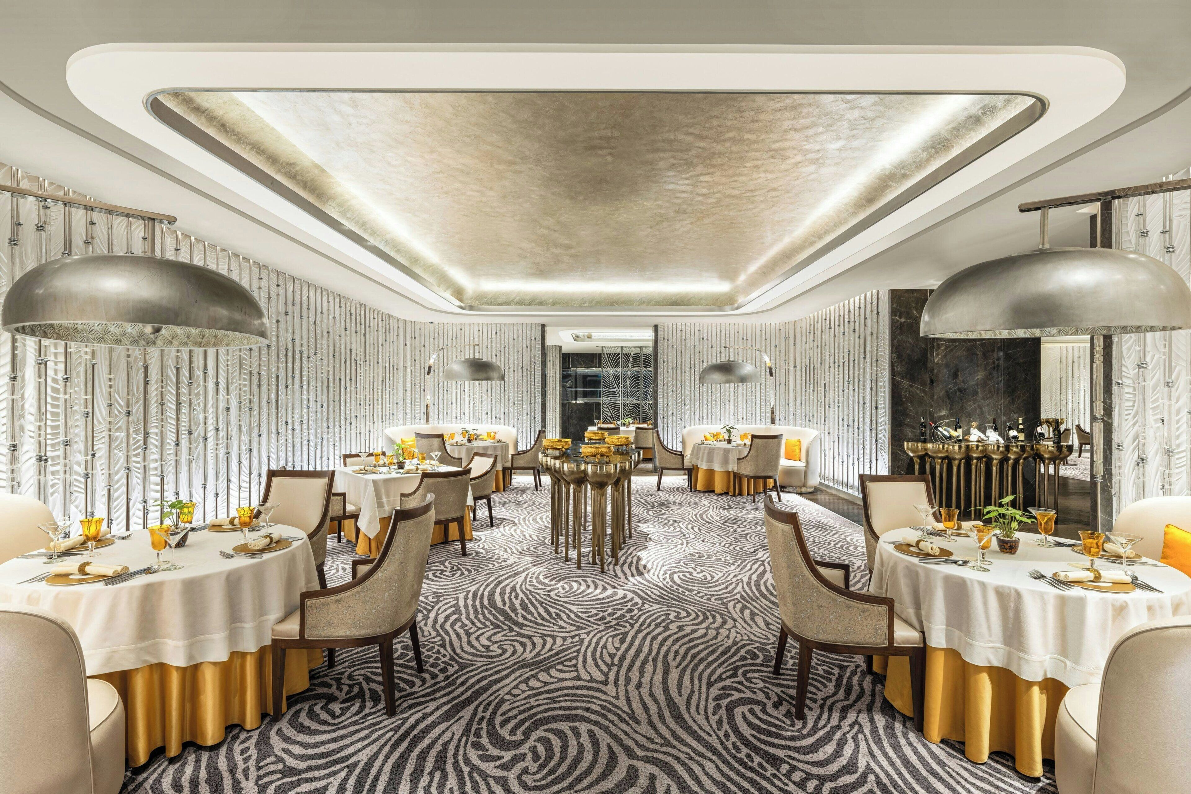 A modern dining area with round tables, gold accents, and a zebra-patterned carpet.