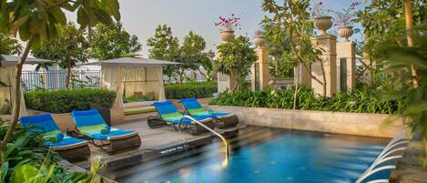 A pool area with lounge chairs, a small gazebo, and potted plants.