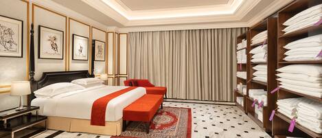 A hotel room with a large bed, a desk, a chair, a wardrobe, and a red rug.