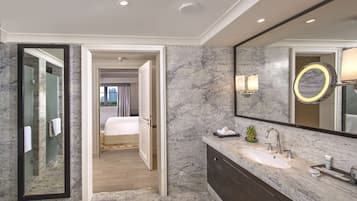 A modern bathroom with a large mirror, marble walls, and a vanity with a sink.