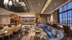 A spacious lobby with a curved seating area, a bar, and a large window providing a view of the city. - ITC Royal Bengal, a Luxury Collection Hotel, Kolkata (Kolkata)