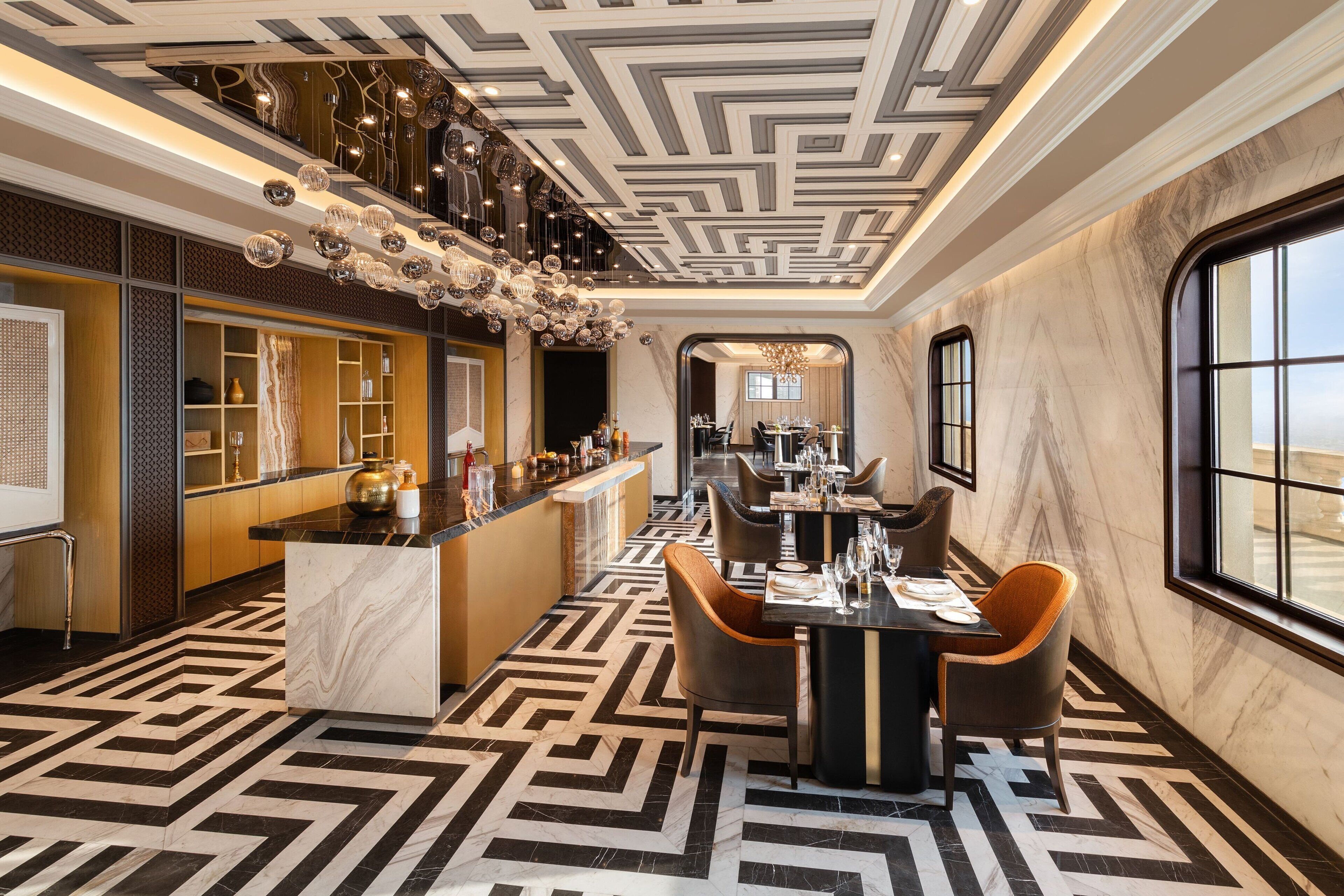 Un moderno vestíbulo de hotel con suelo de diseño geométrico, una zona de bar y un comedor con vistas.