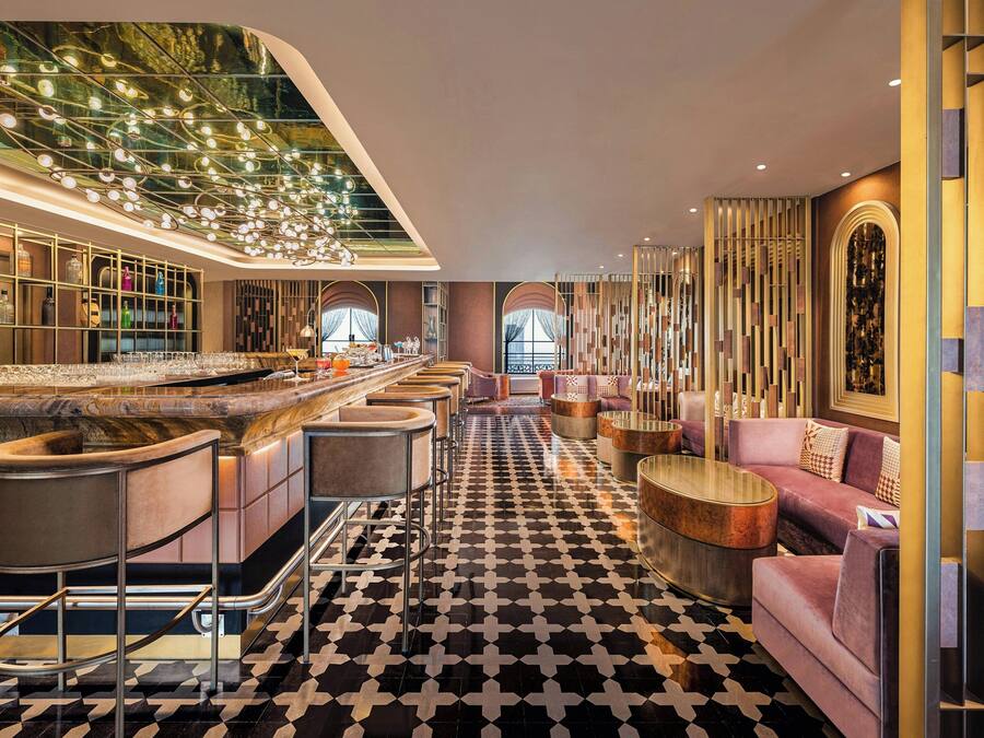 Eine moderne Bar mit Schachbrettmuster-Boden, Barhocker und einer langen Theke.