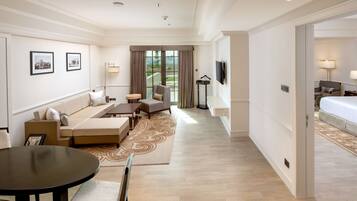A hotel room with a sofa, armchair, dining table, and a bed.