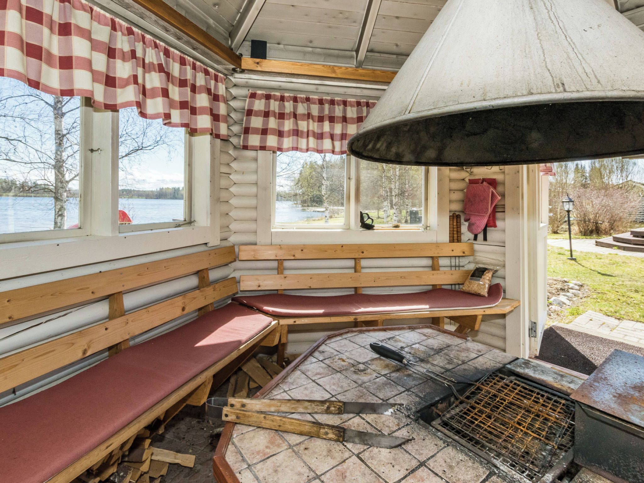 Een blokhutinterieur met een zithoek met een bank, een open haard en uitzicht op de natuur.