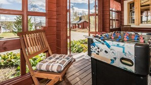 A wooden deck with a foosball table, a bench with a plaid cushion, and a view of a house and trees. - Vacation home Eden by Interhome (Laukaa)