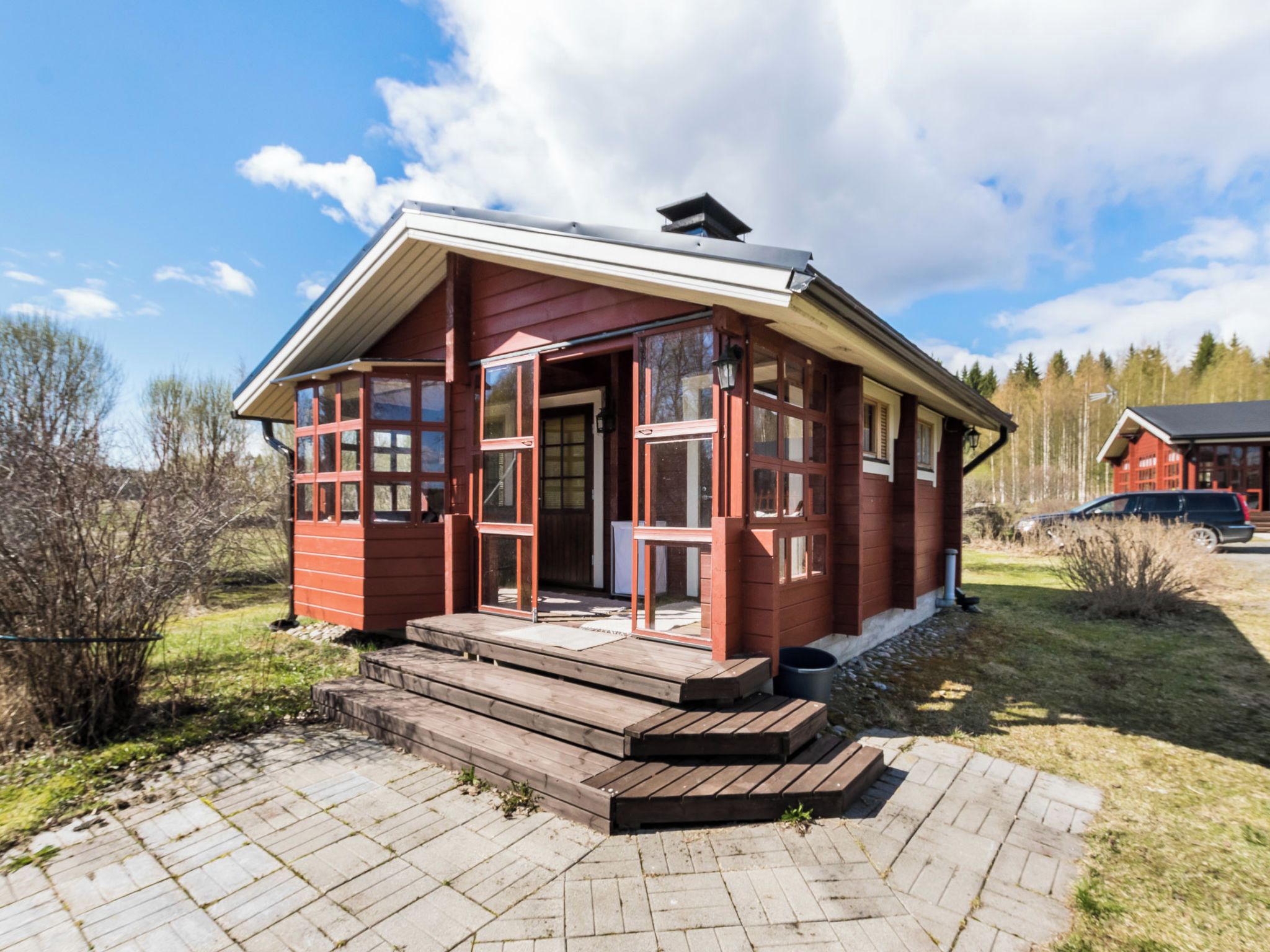 A red wooden cabin with a porch and steps leading to the entrance.