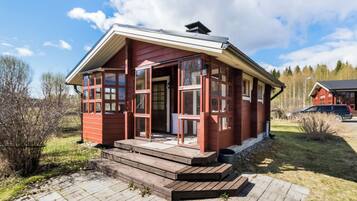 A red wooden cabin with a porch and steps leading to the entrance.