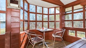A wooden cabin with a corner table and two metal chairs, large windows, and a view of the outdoors. - Vacation home Eden by Interhome (Laukaa)