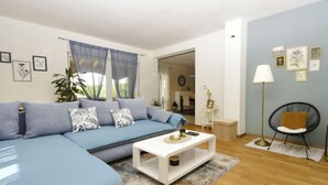 Un salon moderne avec un canapé bleu, une table basse blanche et un fauteuil noir.