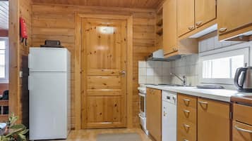 Kompakti keittiö, jossa on puukalusteet, valkoinen jääkaappi, astianpesukone ja ikkuna, josta tulee luonnonvaloa.