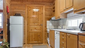 Una cocina compacta con armarios de madera, un refrigerador blanco, un horno empotrado y un lavamanos.