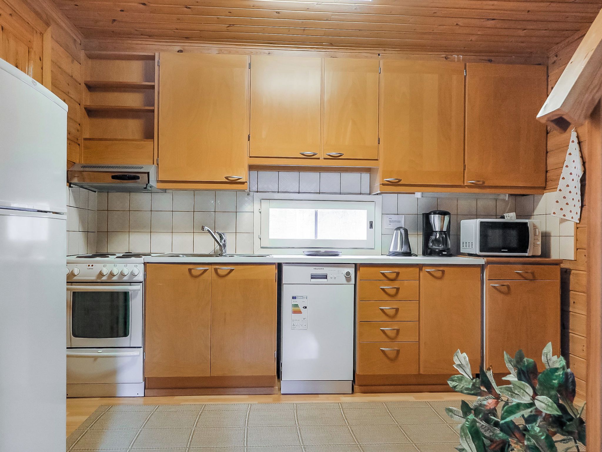 A compact kitchen with wooden cabinets, a built-in oven, a microwave, and a dishwasher.