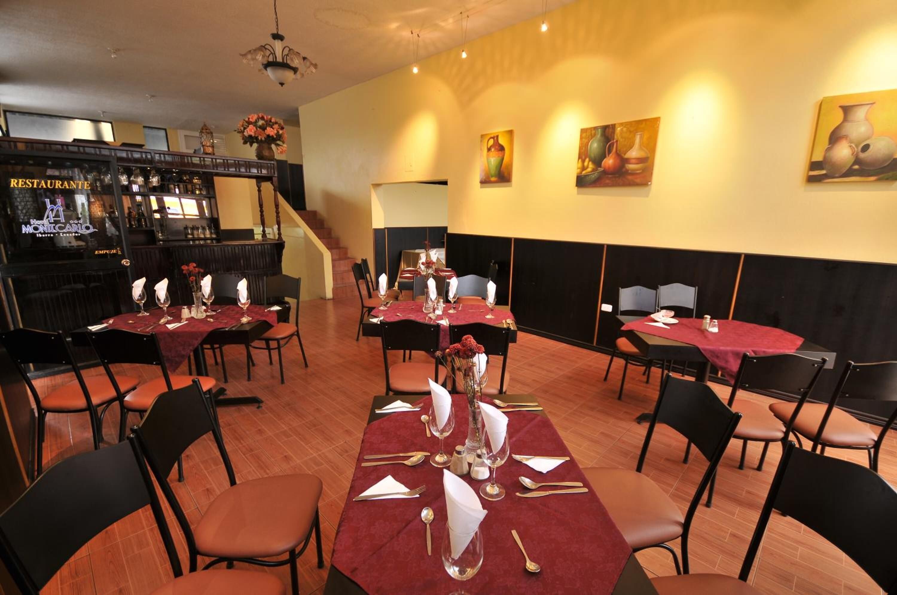 A restaurant with tables set for dining, a bar area, and a staircase leading to an upper level.