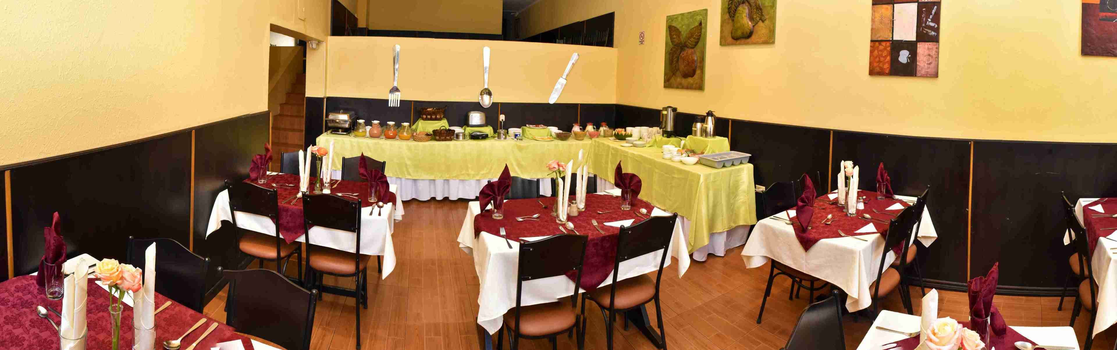 A dining area with multiple tables set for a meal, each with white tablecloths and red napkins.