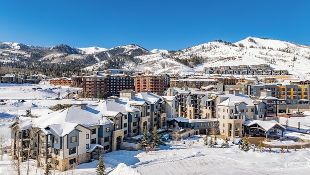 A snow-covered resort with modern multi-story buildings, ski slopes, and a mountainous backdrop. - Luxury hotel room in Canyons Village, mountain view, outdoor pool, hot tub, near hiking & biking (Park City)