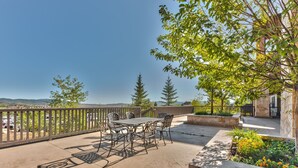 An outdoor patio with a table and chairs, surrounded by stone walls and greenery. - Luxury hotel room in Canyons Village, mountain view, outdoor pool, hot tub, near hiking & biking (Park City)