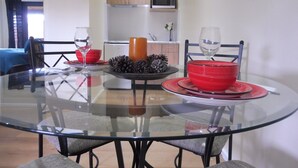Un comedor con una mesa de vidrio, platos rojos y negros, y dos copas de vino.
