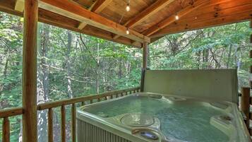 A hot tub in a wooden cabin with a view of a forest.