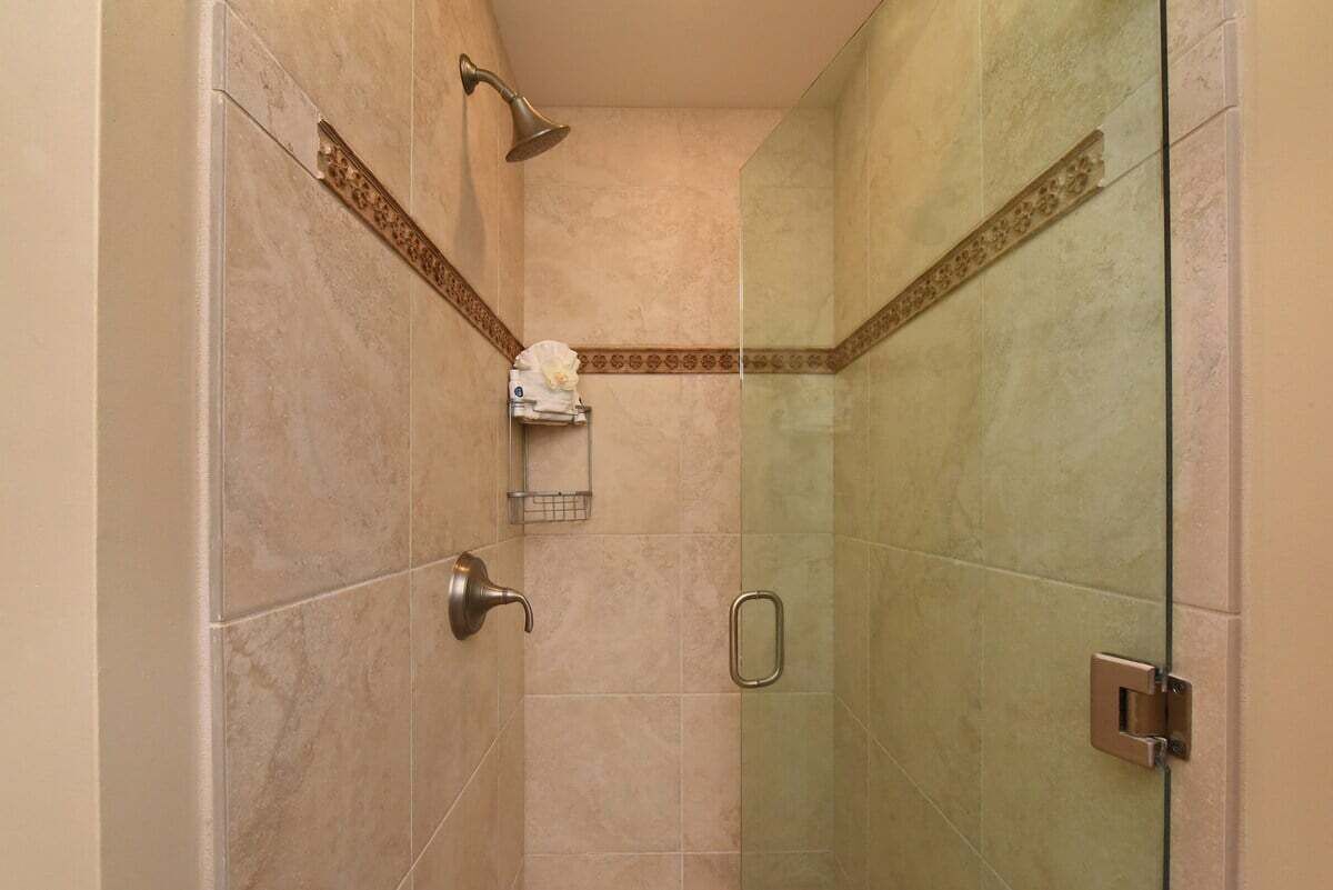 Un área de ducha con puerta de vidrio, toallero y cabezal de ducha.
