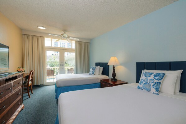 A hotel room with two beds, a desk, and a chair. - Waikiki Heritage Hotel (Honolulu)