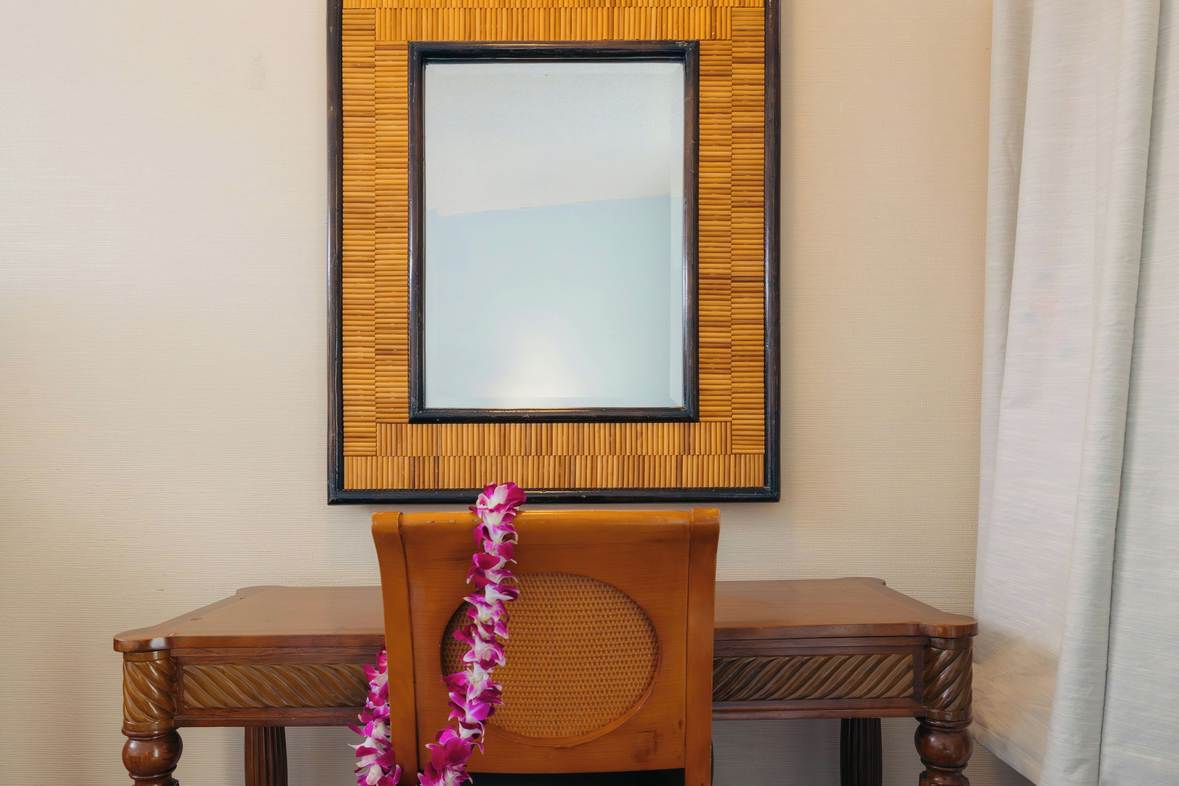 A wooden chair with a woven backrest and a decorative lei.
