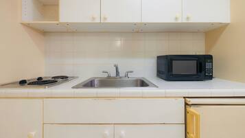 A kitchen with a stove, sink, and microwave.