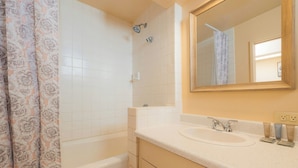 Un baño con bañera, lavamanos, espejo y cortina de ducha.