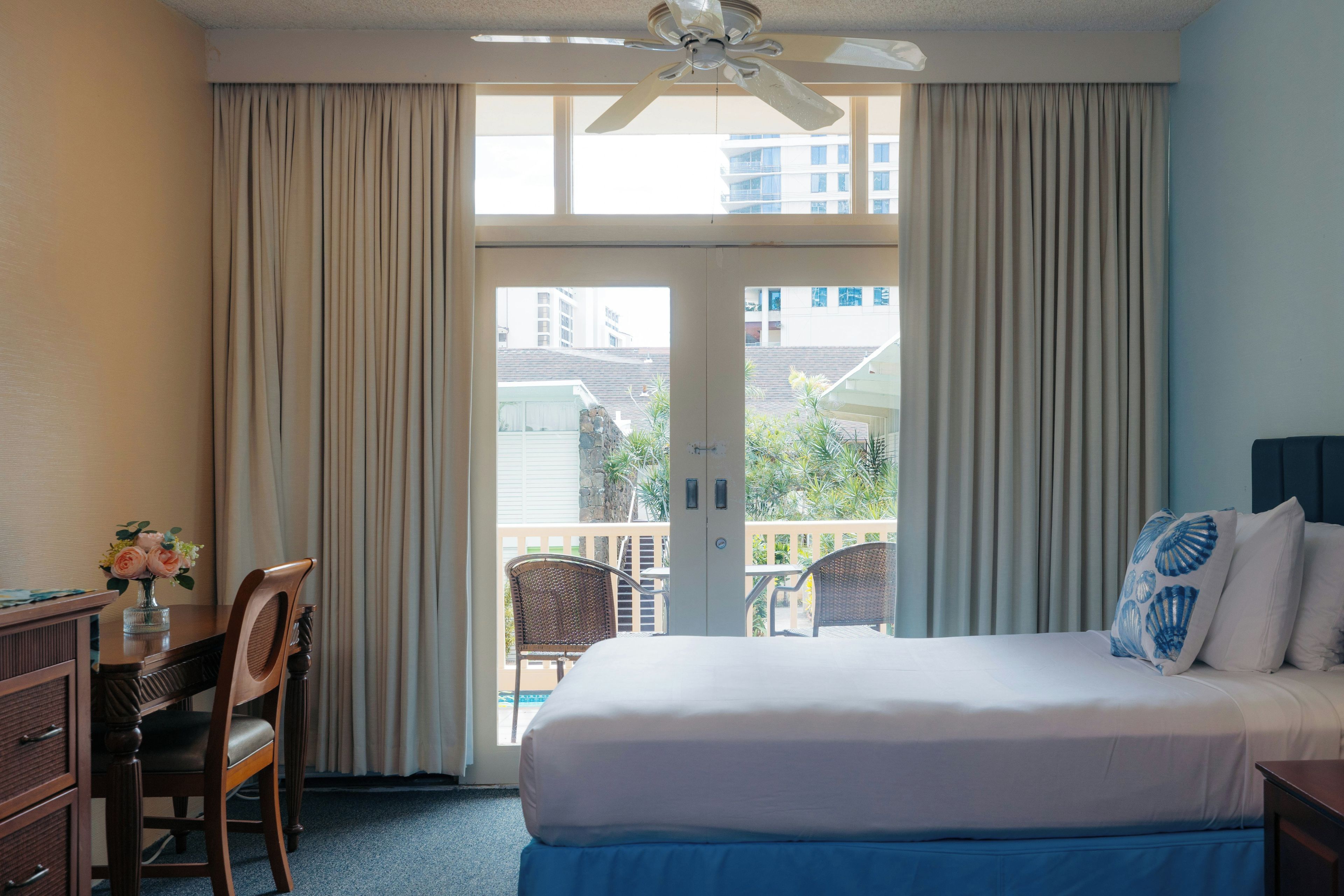 Habitación de hotel con cama, escritorio, silla y vistas al exterior.