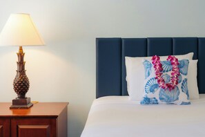 A hotel room with a bed, a nightstand, a lamp, and a decorative pillow. - Waikiki Heritage Hotel (Honolulu)