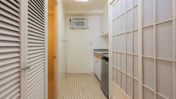 A narrow hallway with a tiled floor, a door with a handle, a white air conditioning unit mounted on the wall, and a tiled wall with a grid pattern.