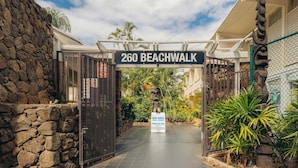 Una entrada cerrada a 260 Beachwalk, con un muro de piedra a un lado y una cerca al otro, que conduce a un sendero pavimentado.