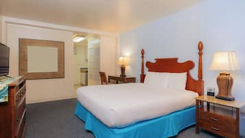 A hotel room with a bed, bedside tables, a desk, a chair, a mirror, and a television.