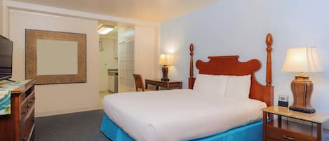 Une chambre d’hôtel comprenant un lit, des tables de chevet, un bureau, une chaise, un miroir et un téléviseur.