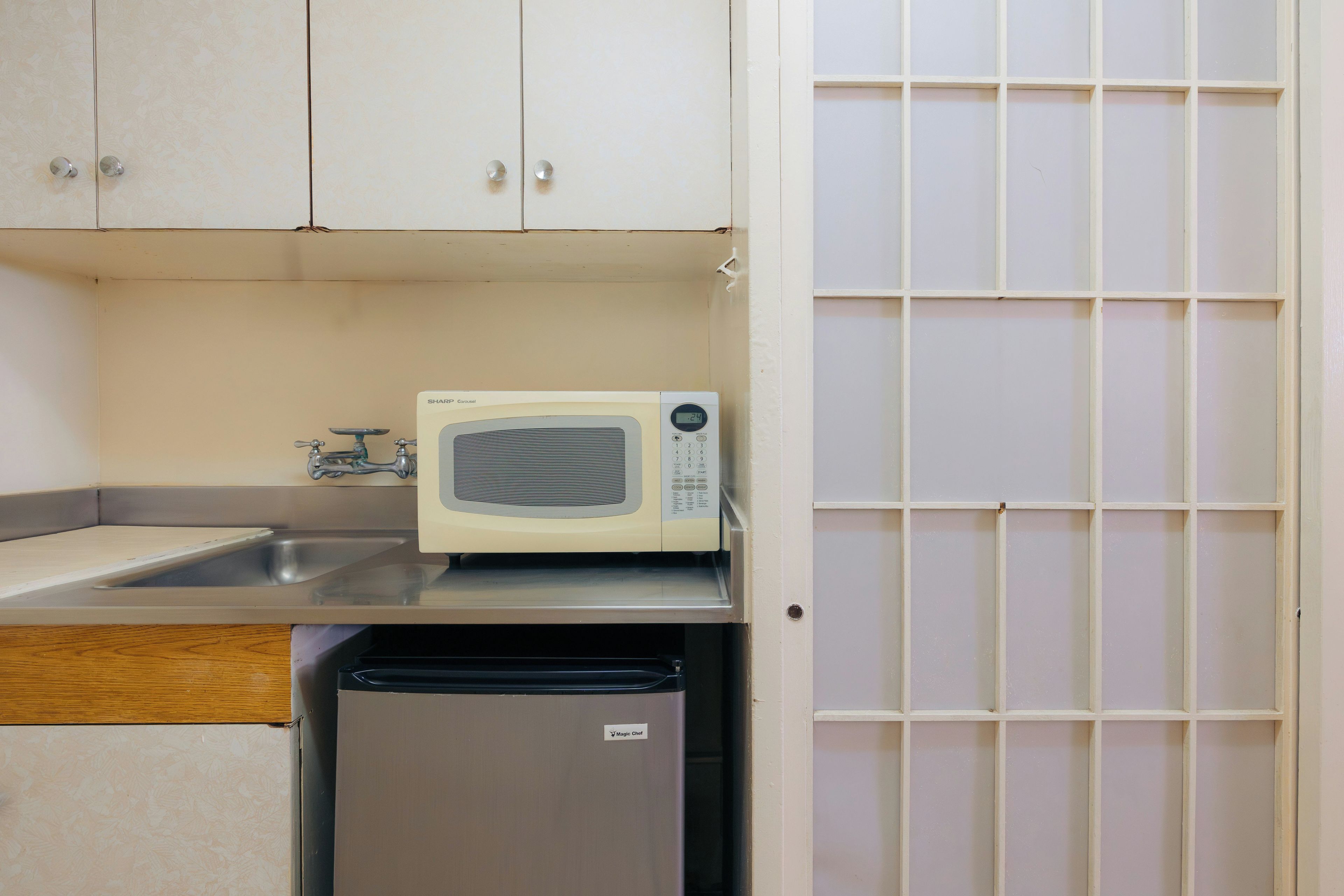 A kitchen with a microwave, a sink, and a small refrigerator.