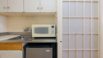 A kitchen with a microwave, a sink, and a small refrigerator.